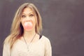 Beautiful blonde girl inflates a red bubble from chewing gum. Close up. Outdoor Royalty Free Stock Photo