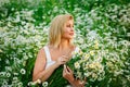 Beautiful blonde girl laughing in a field of daisies at sunset with a bouquet of camomiles Royalty Free Stock Photo