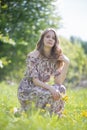 A beautiful girl with a bouquet of first flowers straightens her hair sitting on the lawn of the Park Royalty Free Stock Photo