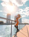 Blonde woman with perfect legs in pantyhose and shoes with high heels posing on the bridge with the Sun Royalty Free Stock Photo