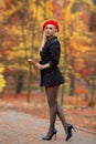 Beautiful blonde girl with perfect legs and red beret posing outdoor on the street of autumn park. Modern Little Red Riding Hood Royalty Free Stock Photo