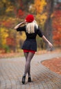 Beautiful blonde girl with perfect legs and red beret posing outdoor on the street of autumn park. Modern Little Red Riding Hood Royalty Free Stock Photo