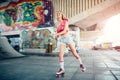 Beautiful blonde girl is riding in rollers in skate room. She is doing that very active. Girl wears pink top and shorts