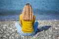 Beautiful blonde girl is sitting on the beach and looking at the Royalty Free Stock Photo