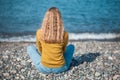 Beautiful blonde girl is sitting on the beach and looking at the Royalty Free Stock Photo