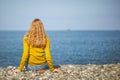 Beautiful blonde girl is sitting on the beach and looking at the Royalty Free Stock Photo