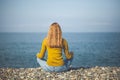 Beautiful blonde girl is sitting on the beach and looking at the Royalty Free Stock Photo