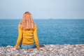 Beautiful blonde girl is sitting on the beach and looking at the Royalty Free Stock Photo