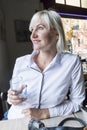 Beautiful blonde girl sitting in a cafe while looking away and she has a camera on the table Royalty Free Stock Photo