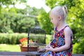 Beautiful blonde girl sitting with a cage on a summer day Royalty Free Stock Photo