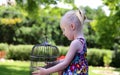 Beautiful blonde girl sitting with a cage on a summer day Royalty Free Stock Photo