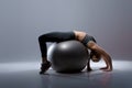 Beautiful blonde girl in sports clothes sitting on fitness ball on dark background Royalty Free Stock Photo