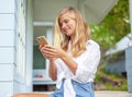 Beautiful blonde girl, on the summer terrace house, with a smartphone in her hands, enjoys sun Royalty Free Stock Photo