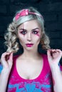 Beautiful blonde girl with two pigtails, with creative doll make-up: pink glossy lips, wearing pink skeleton dress. for the Hallow Royalty Free Stock Photo