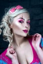 Beautiful blonde girl with two pigtails, with creative doll make-up: pink glossy lips, wearing pink skeleton dress. for the Hallow Royalty Free Stock Photo