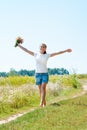 Beautiful blonde girl walking barefoot on summer field with a bouquet of wild flowers Royalty Free Stock Photo