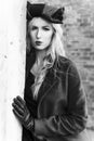 A beautiful blonde girl wearing a red coat and gloves stands at a ruined wall and brick arch near an old building. Fashionable, Royalty Free Stock Photo