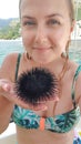 Young girl in a swimsuit holding a black sea urchin in the palm of her hand Royalty Free Stock Photo