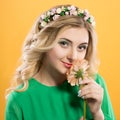 Beautiful blonde girl with a wreath on his head on yellow background. Woman holds gerbera flower near the face. Royalty Free Stock Photo