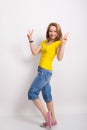 Beautiful blonde girl in the yellow shirt, blue breeches shows gesture Victoria Royalty Free Stock Photo