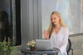 Beautiful blonde hair girl sitting with laptop in front of retails shop,Small business owner concept.