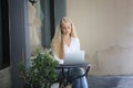 Beautiful blonde hair girl sitting with laptop in front of retails shop,Small business owner concept.