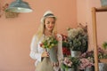 Beautiful blonde hair girl standing with confidence in front of flower in open retails flora shop. Small business owner concept