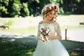 Beautiful blonde happy bride in elegant white dress in a wreath