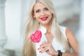 Beautiful blonde with a heart-shaped lollipop Royalty Free Stock Photo