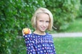 Beautiful blonde kid girl on a walk in the park eats fruit, nectarine or peach. Royalty Free Stock Photo