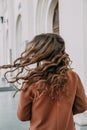 The beautiful blonde lady with curly hair. The back view of a girl. Woman walking down the street. Traveler, summer fashion trend Royalty Free Stock Photo