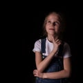 Beautiful blonde little girl on a dark background. She stands in different poses and shows different emotions. free Royalty Free Stock Photo