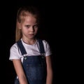 Beautiful blonde little girl on a dark background. She stands in different poses and shows different emotions. free Royalty Free Stock Photo