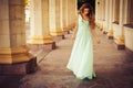 Beautiful blonde with a long curly hair in a long evening dress in static outdoors near retro vintage building in summer sunset Royalty Free Stock Photo