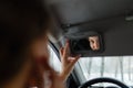 A beautiful blonde looks in a car mirror.