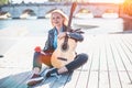 Beautiful blonde middle-aged woman posing during sunset with acoustic guitar Royalty Free Stock Photo