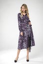 Beautiful blonde model posing in long sleeve, long chic purple dress Royalty Free Stock Photo