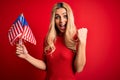 Beautiful Blonde Patriotic Woman Holding United States Flags Celebrating Independence Day Screaming Proud And Celebrating Victory