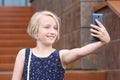 Beautiful blonde preteen girl using a phone, taking a self portrait with mobile phone Royalty Free Stock Photo