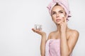 Beautiful blonde woman model holding a cream in her hand and creaming her face with towel on her head Royalty Free Stock Photo