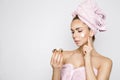 Beautiful blonde woman model holding a cream in her hand and creaming her face with towel on her head Royalty Free Stock Photo