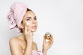 Beautiful blonde woman model holding a cream in her hand and creaming her face with towel on her head Royalty Free Stock Photo