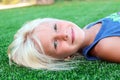 Beautiful blonde smiling girl sitting on the grass on a summer day Royalty Free Stock Photo