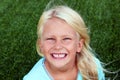 Beautiful blonde smiling girl sitting on the grass on a summer day Royalty Free Stock Photo