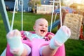 Beautiful blonde smiling girl is swinging outside on a summer day Royalty Free Stock Photo