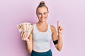 Beautiful blonde sport woman holding 10 united kingdom pounds banknotes smiling with an idea or question pointing finger with