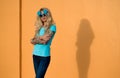 Beautiful blonde in sunglasses posing at the camera. Portrait on the background of bright orange wall. Modern hipster Royalty Free Stock Photo