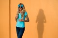 Beautiful blonde in sunglasses posing at the camera. Portrait on the background of bright orange wall. Modern hipster Royalty Free Stock Photo