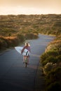 Beautiful blonde surfer girl on her way to the beach on her bicycle with her surfboard. Royalty Free Stock Photo