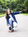 Beautiful blonde teen girl in jeans shirt, on skateboard in park Royalty Free Stock Photo